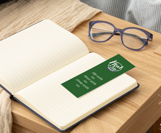 Open book with a green bookmark featuring text and a logo on a wooden surface.